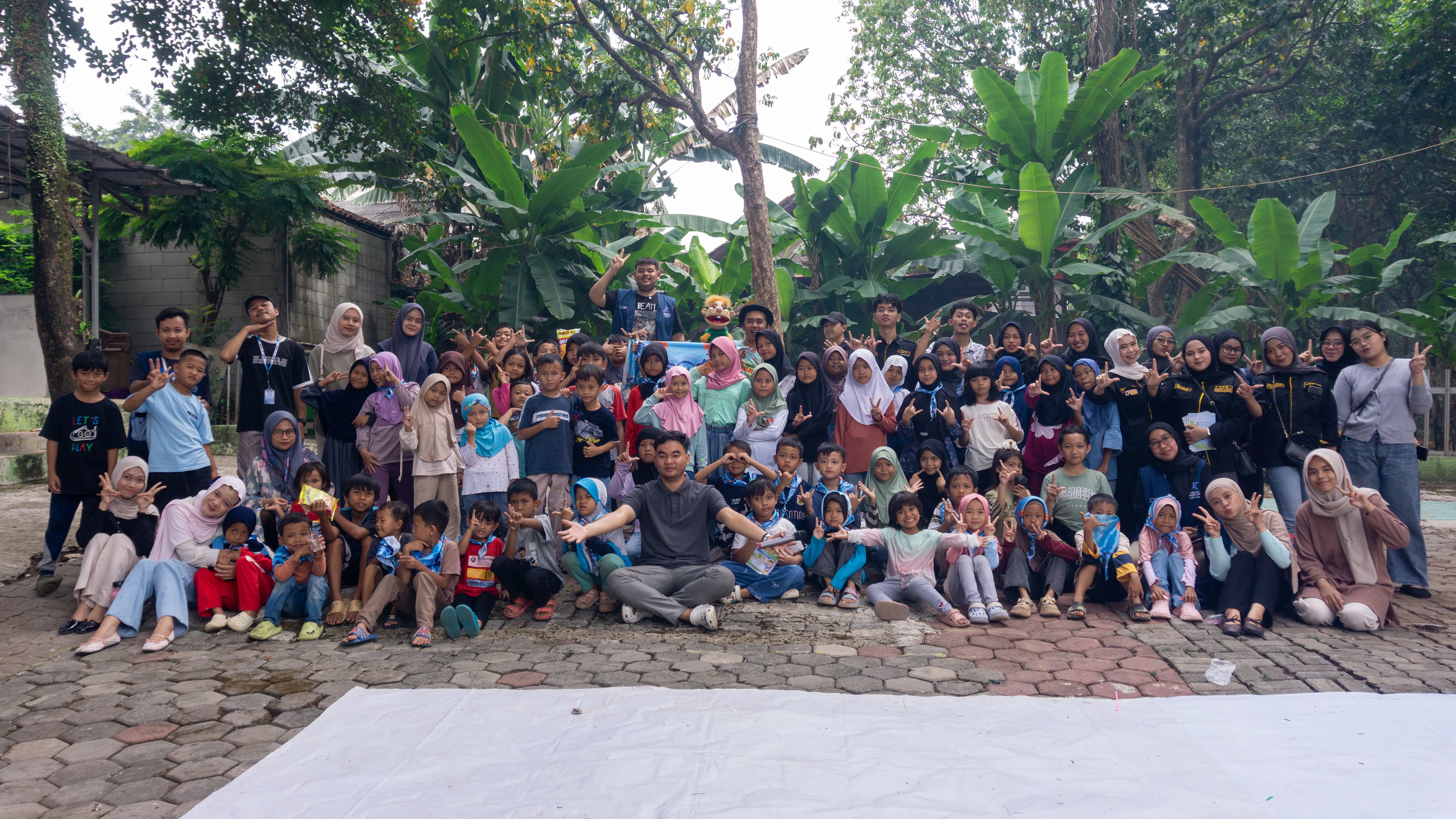 Relawan duduk bersama anak-anak di teras rumah warga
